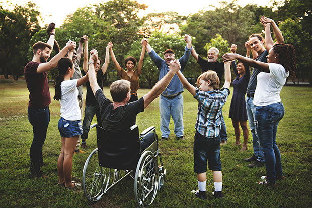 group of people holding hands in a circle on the grass outside